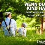 Vater und Kind sitzen aud Wiese, gleich angezogen und mit einem Grashalm im Mund