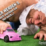 Behaarter Mann spielt wie ein Kind mit einem rosanen Spielzeugauto auf Teppich