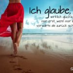 Sprüche über Glück - Frau im leichten roten Kleid spazierend am Strand