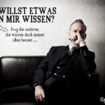 Verschlossener Mann im Anzug auf schwarzem Sofa als nachdenkliches Spruchbild