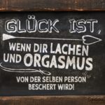 Glück ist Lachen und Orgasmus - Spruch auf Tafel mit Holzumrandung